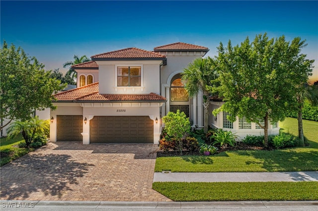 mediterranean / spanish house with a garage and a front lawn