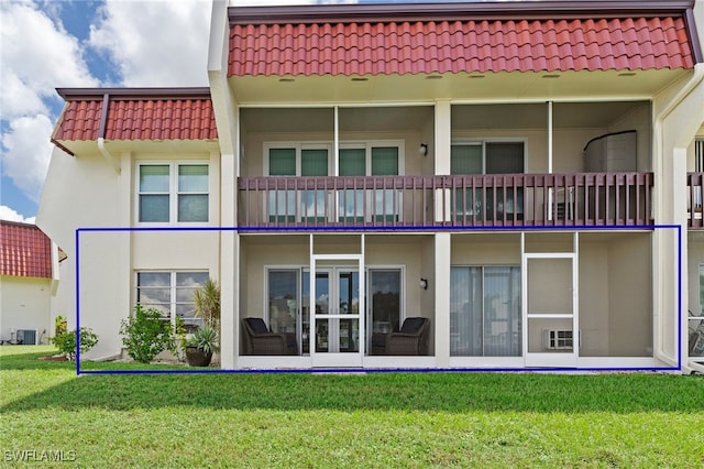 rear view of house with central air condition unit and a lawn