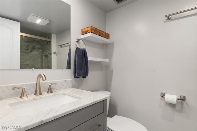 bathroom with vanity, a shower with door, and toilet