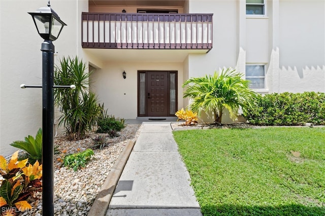 entrance to property featuring a lawn and a balcony