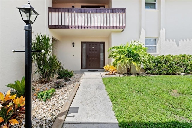 entrance to property featuring a balcony and a yard