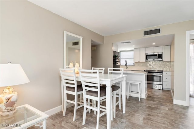 dining room featuring sink and light hardwood / wood-style flooring