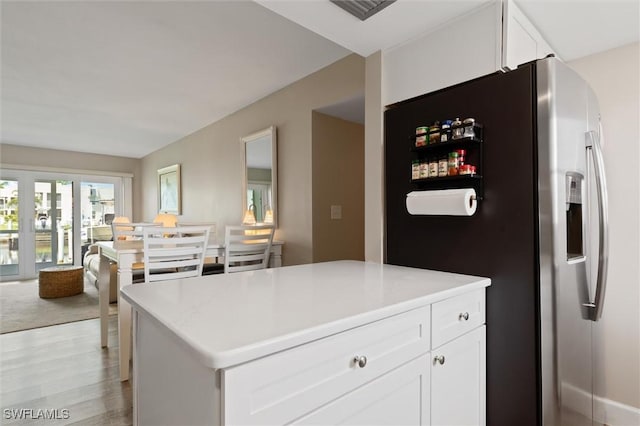 kitchen with white cabinetry, a center island, stainless steel fridge with ice dispenser, and light hardwood / wood-style flooring