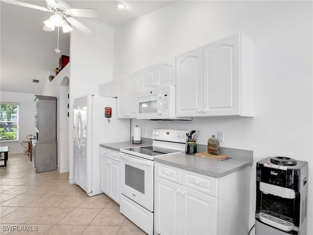 kitchen with white cabinets, light tile patterned floors, heating unit, white appliances, and ceiling fan