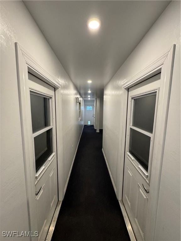 corridor featuring dark colored carpet