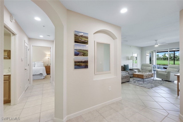 hall featuring recessed lighting, light tile patterned flooring, and baseboards