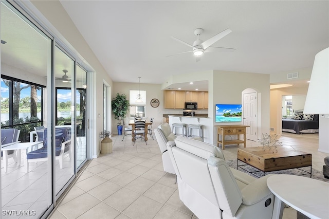 living room with light tile patterned floors, visible vents, and a ceiling fan