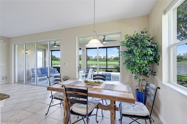 dining space with a water view, baseboards, visible vents, and a wealth of natural light