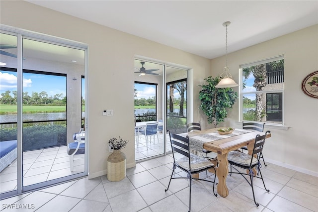 dining area with a water view, baseboards, and light tile patterned flooring