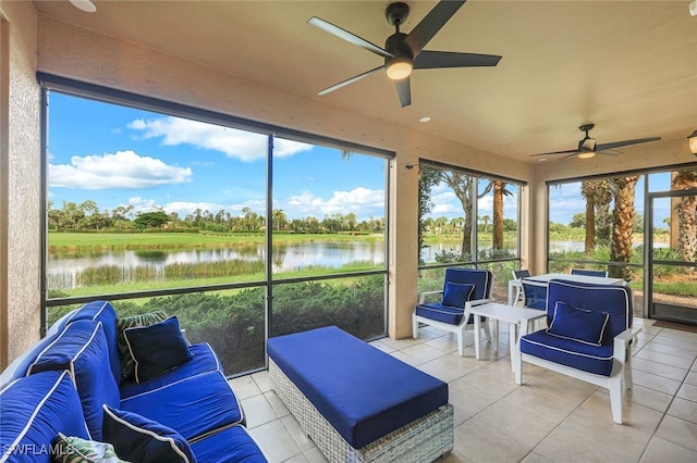 sunroom with ceiling fan and a water view