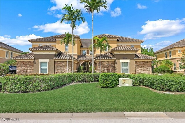 mediterranean / spanish-style home featuring stone siding, a front lawn, and stucco siding