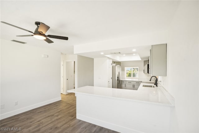 kitchen featuring dark hardwood / wood-style flooring, kitchen peninsula, sink, ceiling fan, and stainless steel refrigerator with ice dispenser