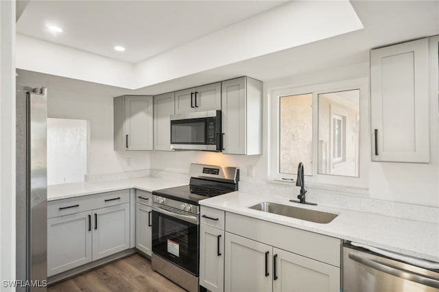 kitchen featuring gray cabinets, stainless steel appliances, light stone counters, sink, and dark hardwood / wood-style floors