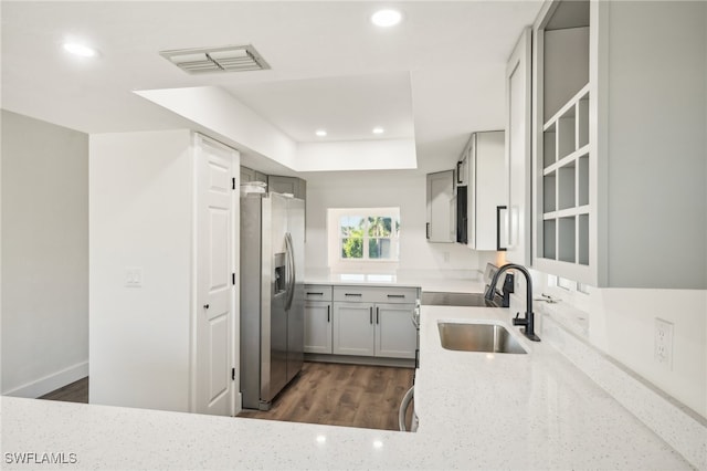 kitchen with stainless steel fridge, light stone counters, dark hardwood / wood-style flooring, and sink