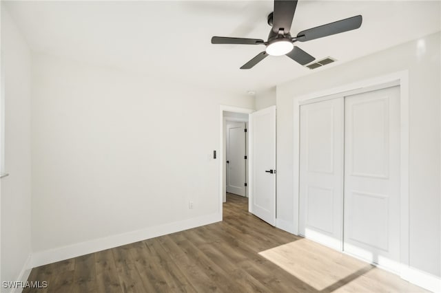 unfurnished bedroom with hardwood / wood-style flooring, ceiling fan, and a closet