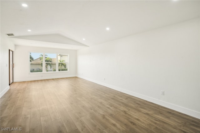 empty room with hardwood / wood-style floors and vaulted ceiling