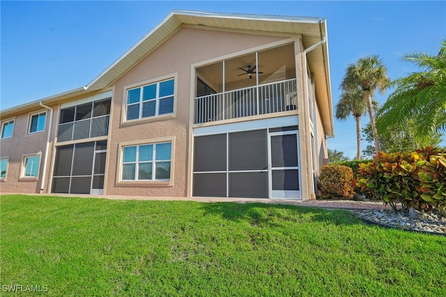 back of property with a lawn, ceiling fan, and a balcony