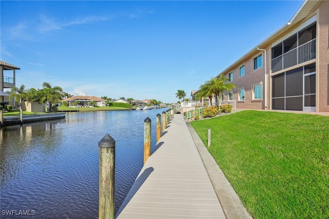 view of dock with a yard and a water view