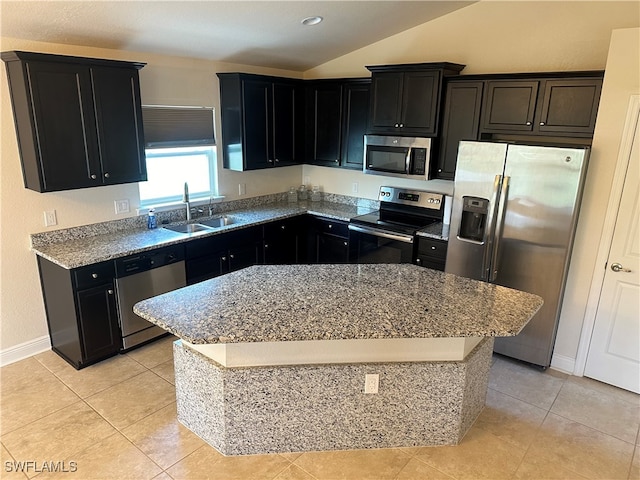 kitchen with light tile patterned floors, a center island, stainless steel appliances, sink, and lofted ceiling