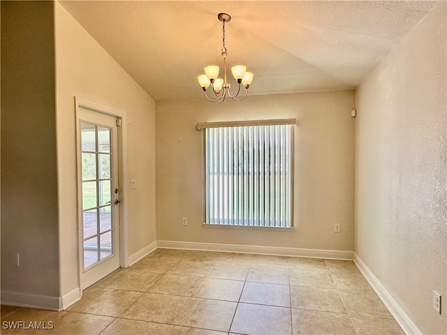 tiled empty room with vaulted ceiling, a textured ceiling, and a notable chandelier