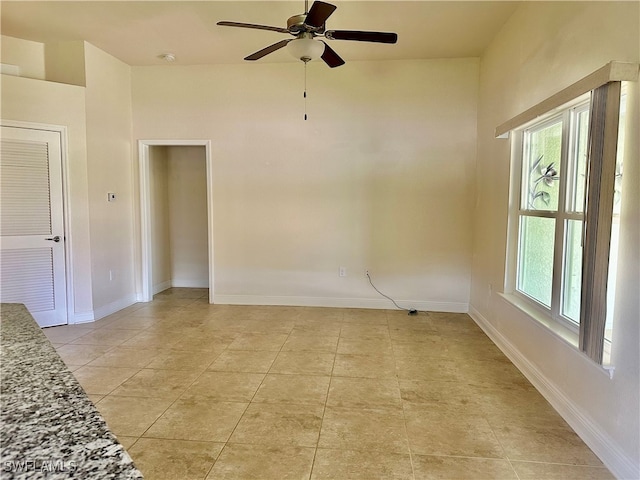 tiled empty room featuring ceiling fan