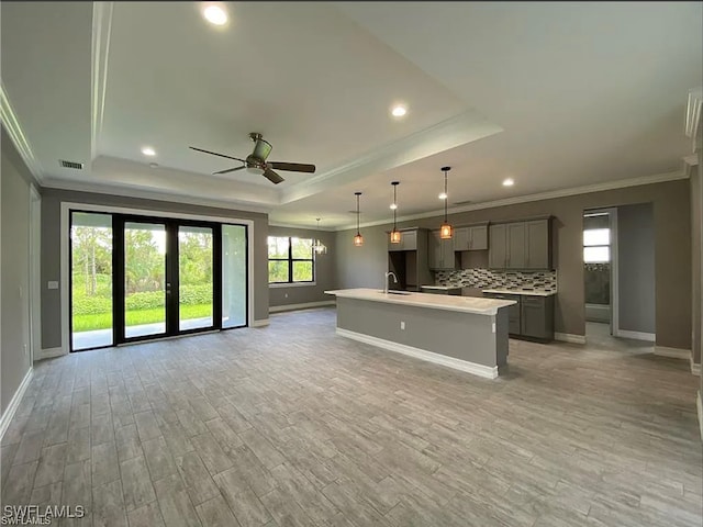 kitchen featuring an island with sink, a healthy amount of sunlight, ceiling fan, and light hardwood / wood-style flooring