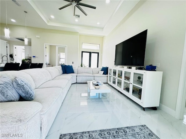 living room with french doors, a towering ceiling, a tray ceiling, and ceiling fan