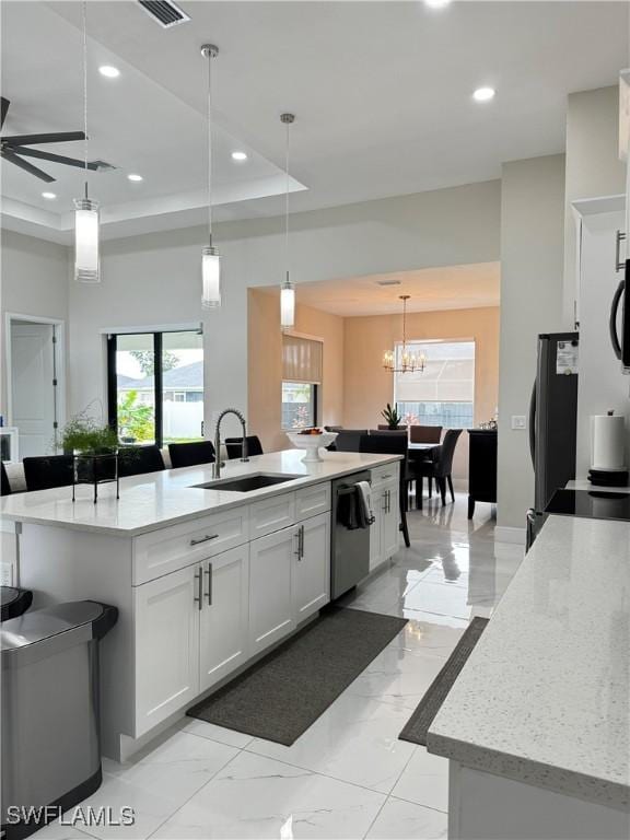 kitchen featuring white cabinetry, sink, a large island with sink, decorative light fixtures, and appliances with stainless steel finishes