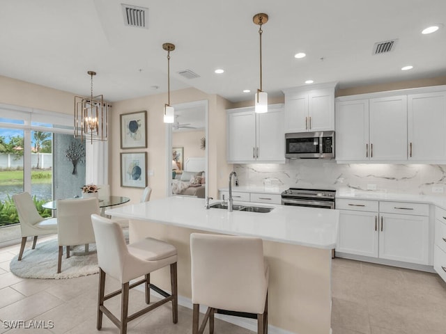 kitchen featuring an island with sink, stainless steel appliances, white cabinetry, and sink