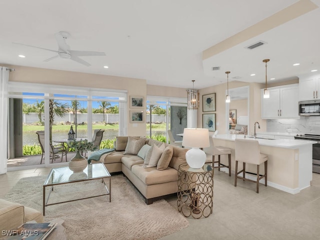 living room featuring light tile patterned floors, ceiling fan with notable chandelier, a wealth of natural light, and sink