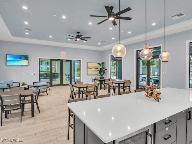 kitchen featuring french doors, a tray ceiling, hanging light fixtures, and ceiling fan