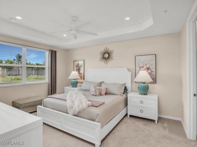 carpeted bedroom with a raised ceiling and ceiling fan