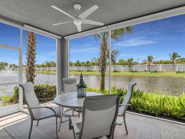 sunroom featuring ceiling fan, a water view, and a healthy amount of sunlight