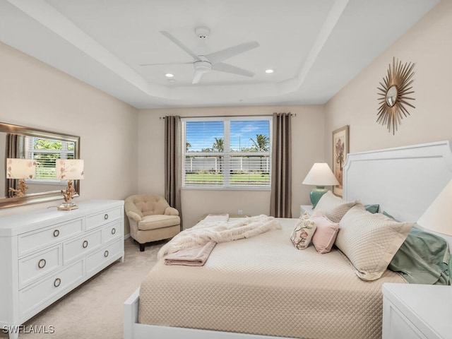 carpeted bedroom featuring ceiling fan and a tray ceiling