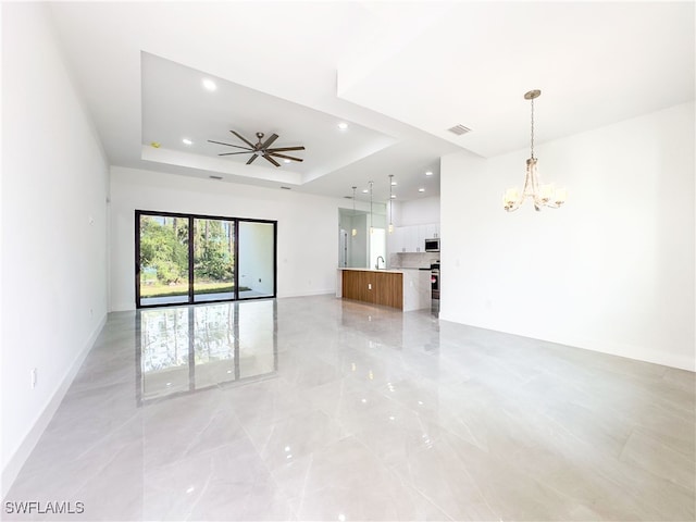 interior space featuring ceiling fan with notable chandelier, sink, and a tray ceiling