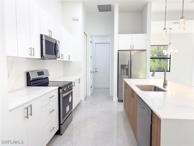 kitchen with pendant lighting, stainless steel appliances, tasteful backsplash, white cabinetry, and sink