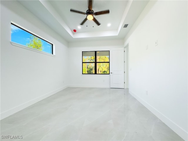 spare room featuring a raised ceiling and ceiling fan