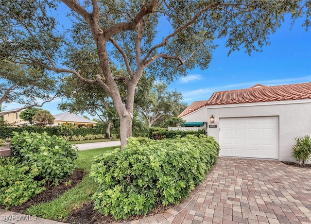 exterior space with a tiled roof, decorative driveway, a garage, and stucco siding