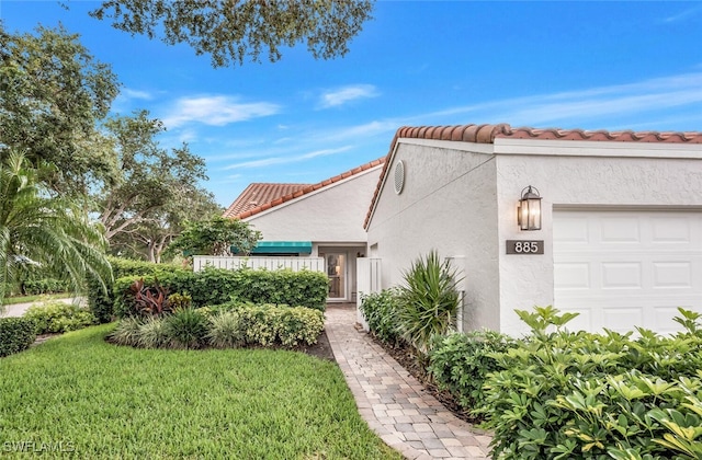 view of front of house featuring stucco siding, an attached garage, a tile roof, and a front yard