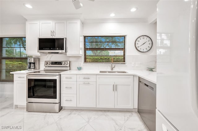 kitchen with a sink, white cabinetry, appliances with stainless steel finishes, crown molding, and light countertops