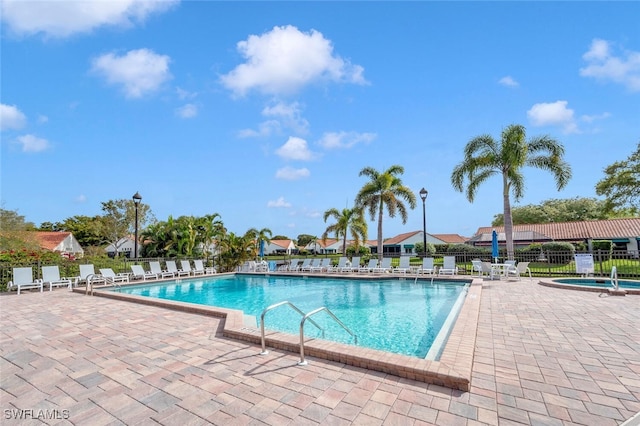 community pool with a patio area and fence