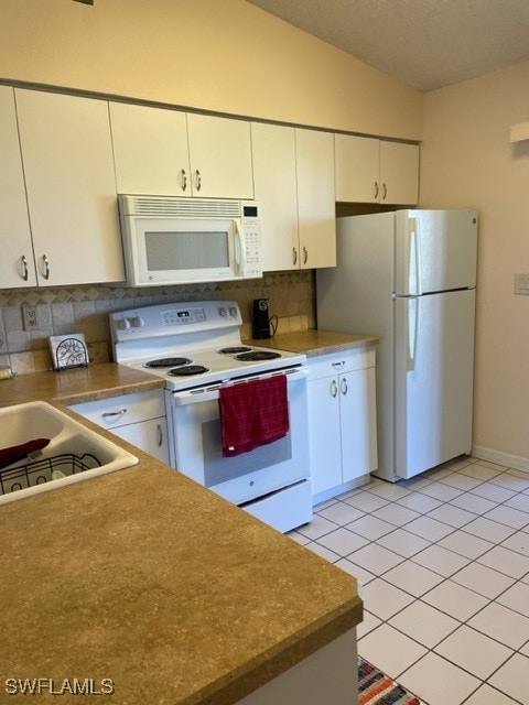 kitchen with white cabinets, backsplash, white appliances, lofted ceiling, and light tile patterned flooring