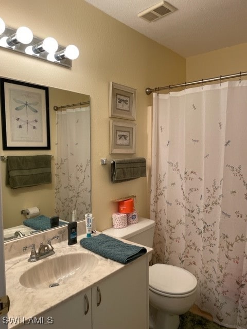 bathroom with a textured ceiling, vanity, and toilet