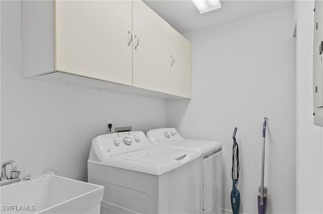 clothes washing area featuring separate washer and dryer, cabinets, and sink