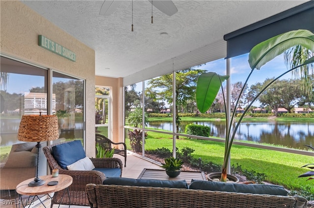 sunroom / solarium with a healthy amount of sunlight, ceiling fan, and a water view