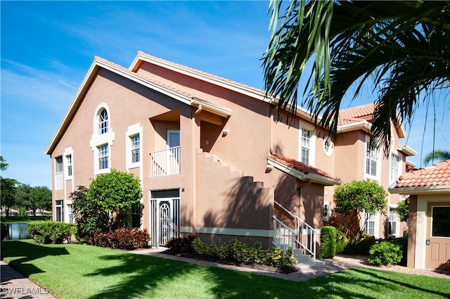 view of front facade with a balcony and a front lawn