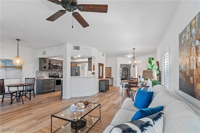 living room featuring light wood-type flooring and ceiling fan with notable chandelier