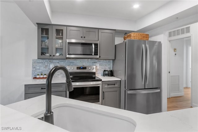 13256 Sherburne Cir Unit 2601, Bonita Springs, FL 34135 - kitchen with stainless steel appliances, gray cabinets, glass insert cabinets, backsplash, and a sink