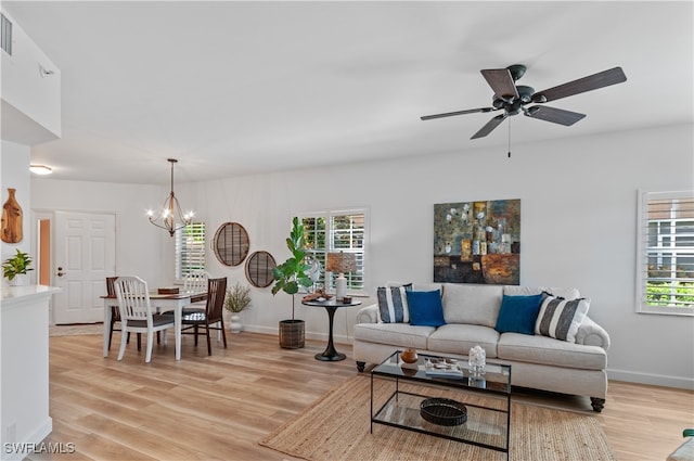 living room with ceiling fan with notable chandelier and light hardwood / wood-style floors