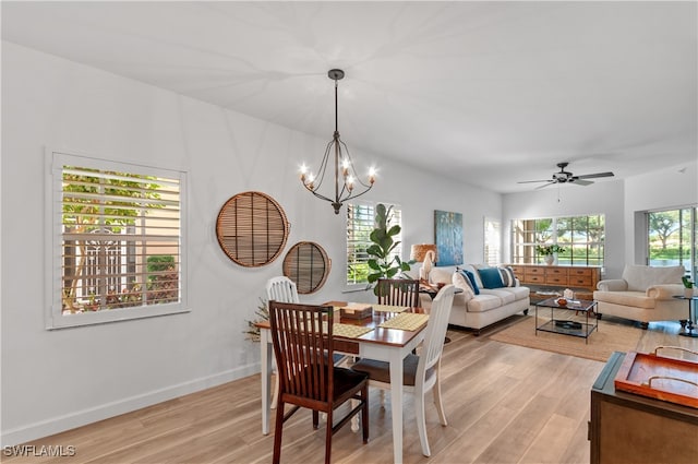 dining area with ceiling fan with notable chandelier and light hardwood / wood-style floors